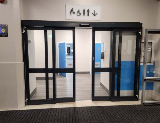 Automatic sliding doors UK with sensor-operated glass panels at retail entrance